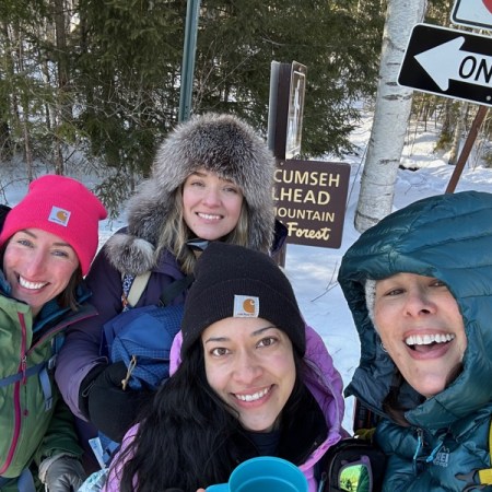 four hikers in front of trailhead sign