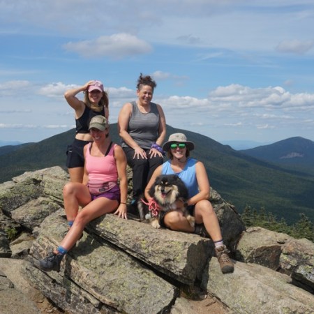 four hikers sitting on rocks on the summit of Mount Liberty